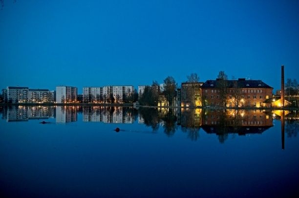 Näkymä Oulun rannasta ja rakennusten heijastuksia vedessä sinisen hetken aikaan.