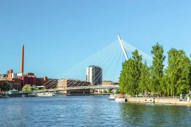 Laukonsilta ja punatiilinen tehdasrakennus Tampereella aurinkoisena päivänä.