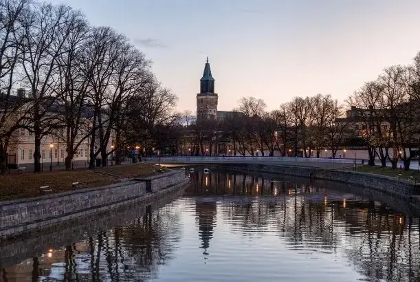 Valaistu Turun tuomiokirkko ja Aurajoki iltahämärässä kuvattuna.
